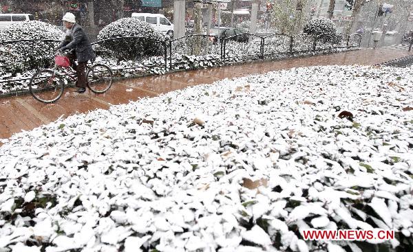 A woman rides her bike in snow in east China&apos;s Shanghai, Dec. 15, 2010. Various parts of China, including Shanghai, embraced the first snow of this winter on Wednesday. A low temperature alarm has been issued by local meteorological department. 