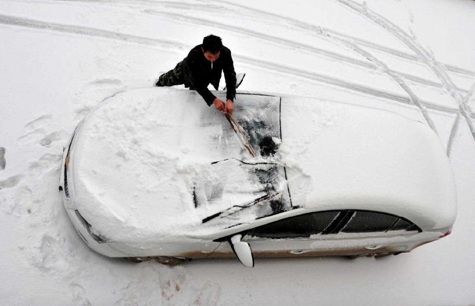 A villager clears away the snow covering his car in Jianshi county, Central China&apos;s Hubei province, Dec 15, 2010. [Xinhua]