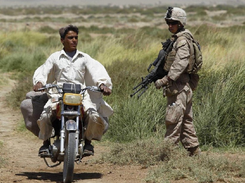 A villager drives his motorcycle past a U.S. marine from 1st Light Armoured Reconnaisance Battalion, Alpha Company patrolling an area in Taghaz village in Helmand, Afghanistan September 9, 2010. [China Daily]