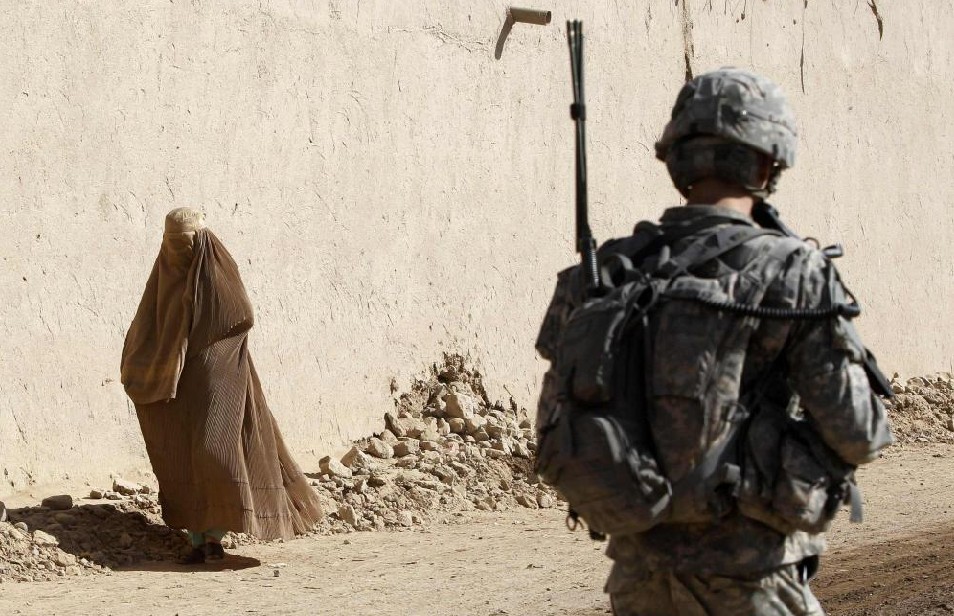 An Afghan woman wearing a burqa walks near a U.S. soldier from 3rd Platoon, Bravo Company, 1-22 Infantry Batallion patrolling in Shingkay village in Kandahar province in southern Afghanistan October 4, 2010. [China Daily]