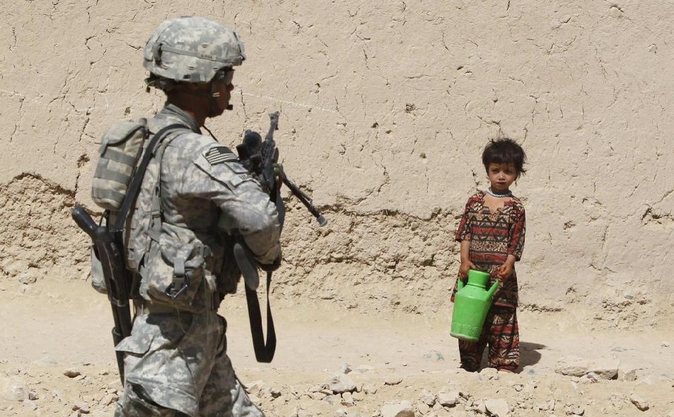 An Afghan girl looks a at a U.S. soldier from 3rd Platoon, Bravo Company, 1-22 Infantry Batallion patrolling in Shingkay village in Kandahar province in southern Afghanistan October 4, 2010. [China Daily]