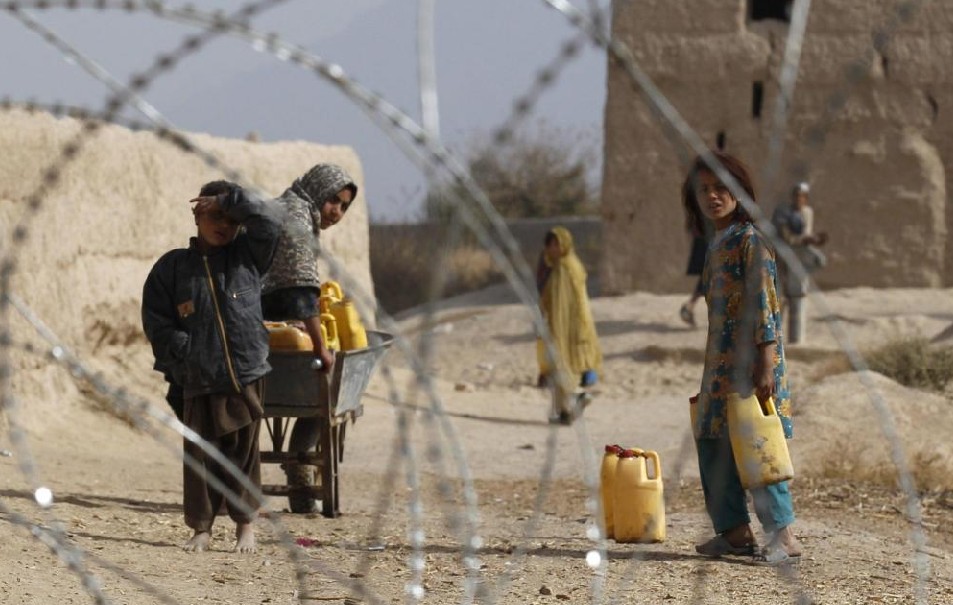 Afghan children look from behind a razor wire at an outpost in Zhari district in Kandahar Province, Afghanistan November 20, 2010.[China Daily]