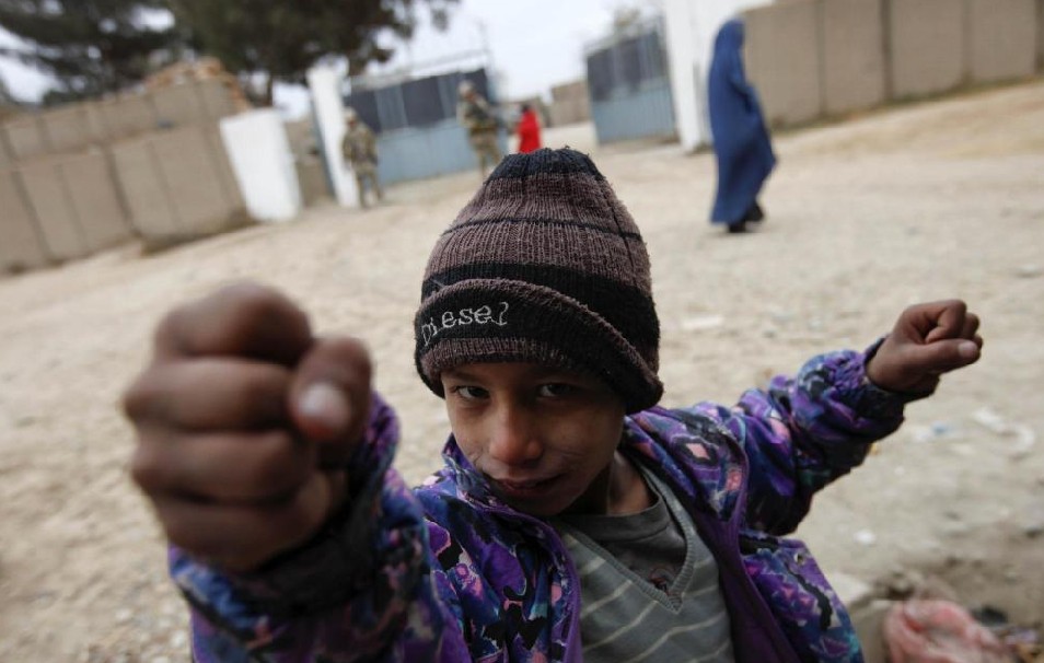 An Afghan boy gestures in front of a combat outpost during a mission of German Bundeswehr army soldiers with the Delta platoon of the 2nd paratroop company 373 in the city of Iman Sahib, north of Kunduz, northern Afghanistan, December 6, 2010. [China Daily]