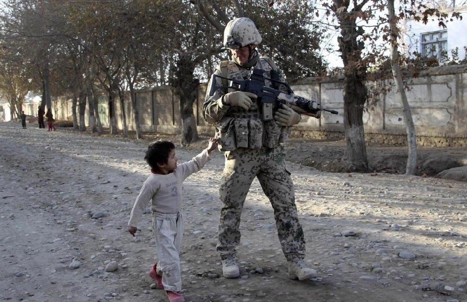 A boy follows a German Bundeswehr army soldier with the 2nd Paratroop Company 373 as he patrols during a mission in the city of Iman Sahib, north of Kunduz, northern Afghanistan December 9, 2010. [China Daily]