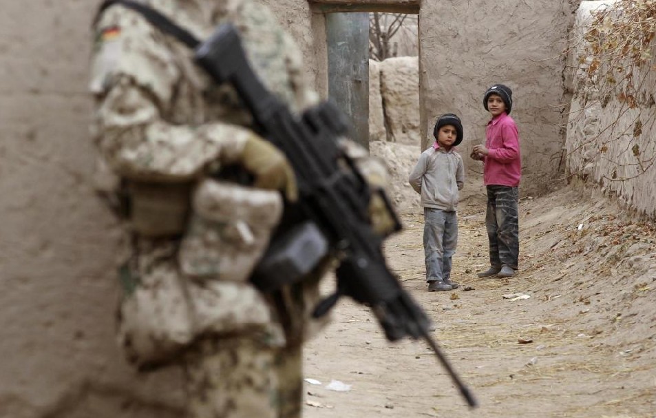 Afghan children look on at a German Bundeswehr army soldier from Charlie platoon of the 2nd Paratroop Company 373 during a mission in the city of Iman Sahib, north of Kunduz, northern Afghanistan, December 15, 2010. [China Daily]