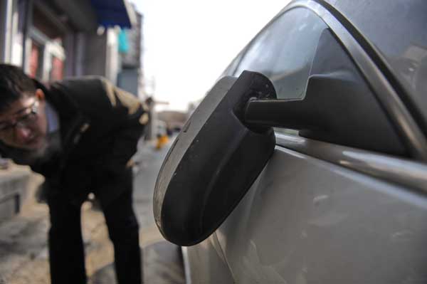 Lawyer Zhang Kai checks damage to his car, which he said was attacked on Tuesday night. 