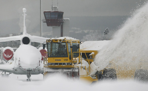 Workers use a blower to remove snow from the tarmac of Zurich airport in Kloten after the region was hit by strong snow falls, Dec 17, 2010. [China Daily/Agencies]