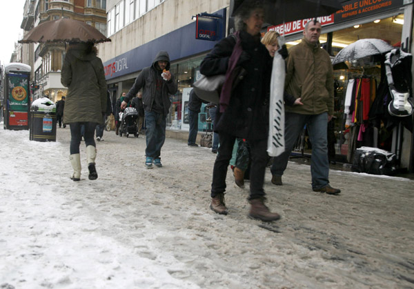 Shoppers walk along Oxford Street, in central London December 18, 2010. Fresh snow brought much of Britain to a standstill on Saturday, on what is traditionally the busiest weekend for shopping and travel in the run-up to Christmas.