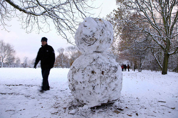 A man walks past a snowman on Wandsworth Common after heavy snow falls in London December 18, 2010. Fresh snow brought much of Britain to a standstill on Saturday, on what is traditionally the busiest weekend for shopping and travel in the run-up to Christmas.