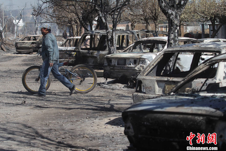 A man walks past burnt cars at the site of an explosion of a Pemex pipeline in the village of San Martin Texmelucan near Puebla Dec 19, 2010. [photo/chinanews.com]