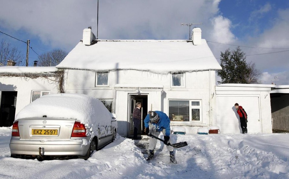 David Higgins (C) clears snow from the driveway of a house in the vilage of Martinstown in the Glens of Antrim, Northern Ireland Dec 19, 2010. The severe weather led to more disruption across Northern Ireland on Sunday, and people were advised to avoid unnecessary road journeys as snow continued to cause travel problems, local media reported. [China Daily/Agencies]