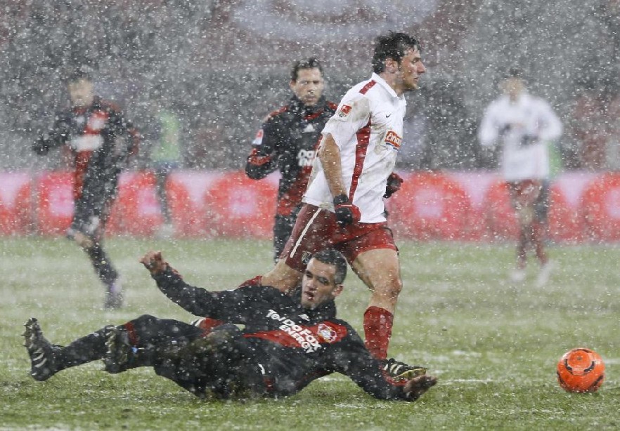 Bayer Leverkusen&apos;s Renato Augusto of Brazil slides in the snow as SC Freiburg&apos;s Stefan Reisinger runs with the ball during their German first division Bundesliga soccer match in Leverkusen Dec 19, 2010.[China Daily/Agencies] 