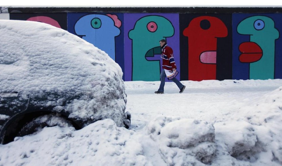 A man walks past a snow-covered car parked at the East Side Gallery in Berlin, Dec 19, 2010. [China Daily/Agencies]