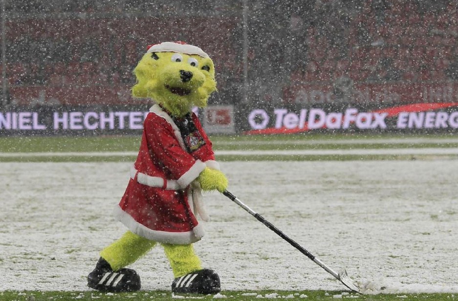 The worker dressed as a mascot of Bayer Leverkusen shovels snow during half time of his team&apos;s German first division Bundesliga soccer match against SC Freiburg in Leverkusen Dec 19, 2010. [China Daily/Agencies] 