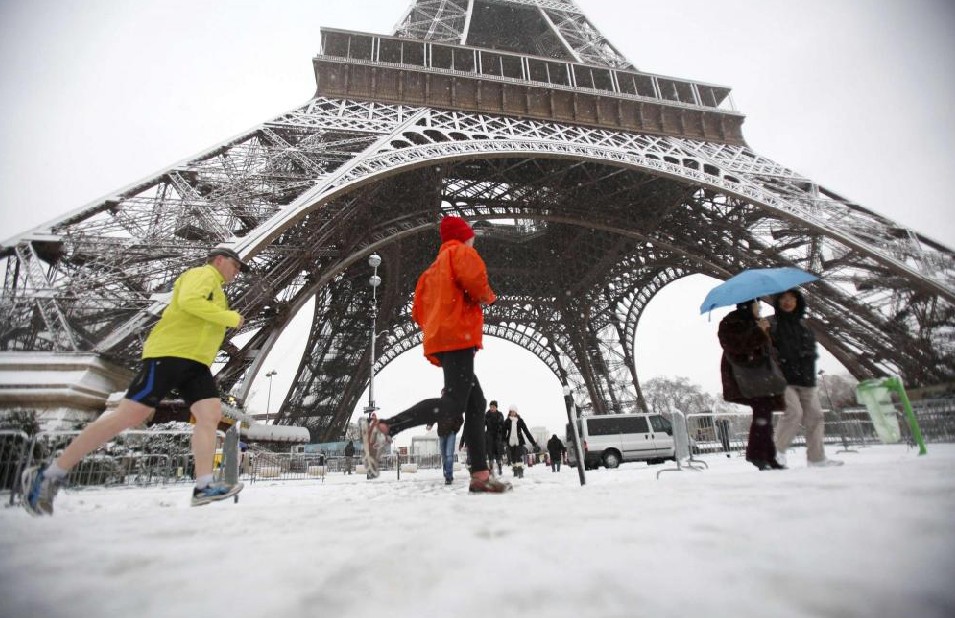  Joggers pass the Eiffel Tower during a heavy snowfall in Paris Dec 19, 2010.[China Daily/Agencies]