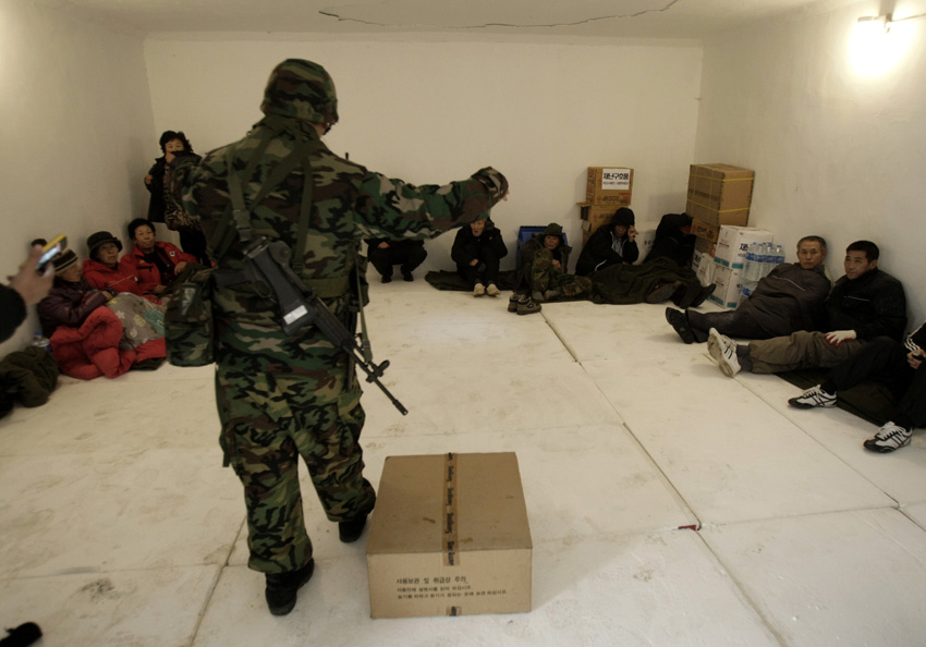 A soldier teaches South Korean residents how to wear gas masks after taking shelter on Yeonpyeong Island, South Korea, December 20, 2010. [Xinhua]
