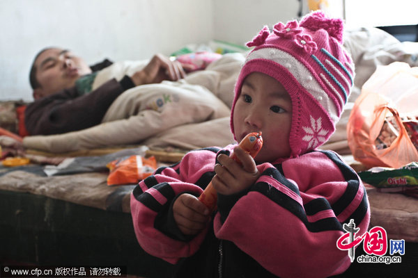 Three-year-old Dong Xinyi helps prepares lunch for her father, who is paraplegic, Dec 19, 2010. [CFP]