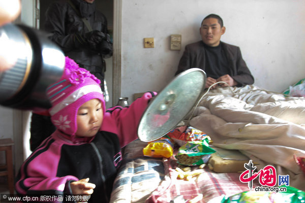 Three-year-old Dong Xinyi helps prepares lunch for her father, who is paraplegic, Dec 19, 2010. [CFP]