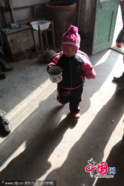 Three-year-old Dong Xinyi helps prepare water for her paralyzed father in Huangjia town of East China&apos;s Shandong province, Dec 19, 2010. Dong Jian, lost the use of his legs after a traffic accident in 2007. His wife then left him and now Dong Xinyi tries to take care of her father. [CFP]