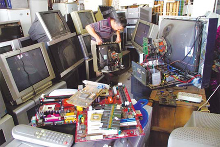 An employee of a waste recycling station in Nanjing, capital of Jiangsu province, sorts through discarded electrical appliances on Aug 3. [China Daily] 