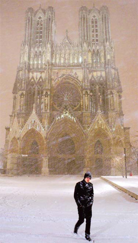 A man walks in front of the Notre-Dame de Reims cathedral as snow falls heavily on Saturday in Reims, northern France. [agencies]