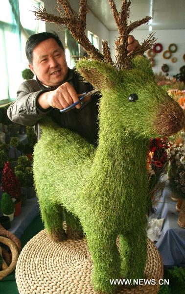 A craftsman trims a reindeer made from grass in Linyi of east China&apos;s Shandong Province, Dec. 18, 2010. A craftwork manufacturer in Linyi designs and makes eco-friendly Christmas decorations with grass, wicker, iron wires, etc, and the Christmas products of the manufacturer are welcomed in European and American countries.