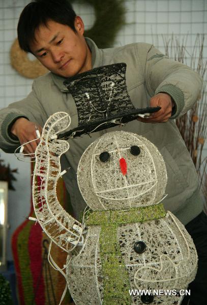 A craftsman trims a snowman made from iron wires in Linyi of east China&apos;s Shandong Province, Dec. 18, 2010. A craftwork manufacturer in Linyi designs and makes eco-friendly Christmas decorations with grass, wicker, iron wires, etc, and the Christmas products of the manufacturer are welcomed in European and American countries. 