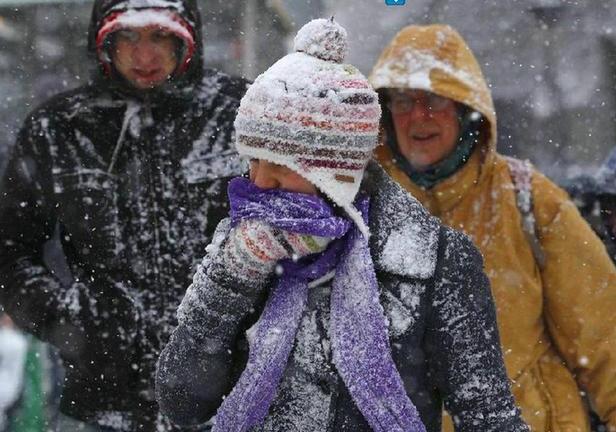 A woman covers her face as she walks in snow in Edinburgh, Scotland Dec 19, 2010. Britons Sunday faced little respite from the Arctic conditions that have disrupted travel and shopping plans on the last weekend before Christmas, normally one of the busiest times of the year. 