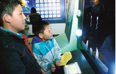 Xia Wu (right), a student from No 3 Primary School in Beijing's Huairou district, learns about how sperm meets the egg by playing an interactive game at a sex education exhibition last week.
