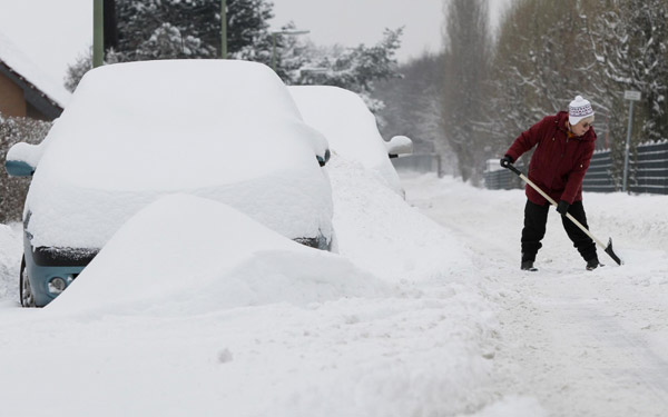 A woman cleans the area in front of her house after snowfall in Berlin December 20, 2010. [China Daily/Agencies] 