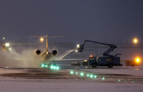 An aircraft is de-iced on the snow covered tarmac of Zaventem international airport near Brussels December 19, 2010. [China Daily/Agencies] 