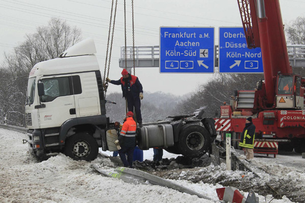 A truck which blocked the A3-A4 motorway intersection Cologne-East is lifted by a crane after it crashed during the night due to icy and snowy road conditions near Cologne December 20, 2010. [China Daily/Agencies] 