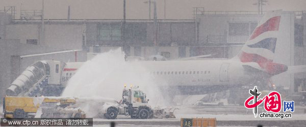 A snow plough passes a British Airways aircraft as it clears snow from a taxi way at Heathrow Airport on December 20, 2010 in London, England. Severe weather has caused major disruption at the United Kingdom&apos;s biggest airport. One runway is closed and all short-haul flights have been cancelled. [CFP]