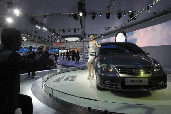 A visitor takes a picture of a model posing in front of a Honda Everus at the Guangzhou Autoshow Dec 20,2010. Guangqi Honda Automobile Co Ltd, a venture between Japan&apos;s Honda Motor Co and Guangzhou Automobile Group, will begin selling its new self-owned Everus brand car in the first half of 2011, executives told reporters on Monday. [Agencies]