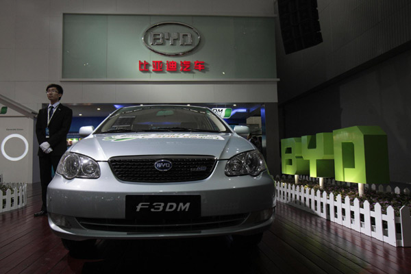 An employee stands near a F3DM, a hybrid car by Chinese automaker BYD Auto, at the Guangzhou Autoshow Dec 20,2010. [Agencies]