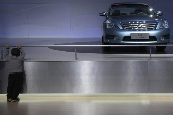 A child stands in front of a Nissan Teana car at the Guangzhou Autoshow Dec 20, 2010. [Agencies]