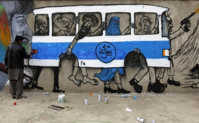 An Afghan artist paints graffiti on the wall of an industrial park in Kabul Dec 19, 2010. The bus on the wall with no wheels and crammed with passengers is a stark comment on war-torn Kabul&apos;s appalling public transport. [China Daily/Agencies]