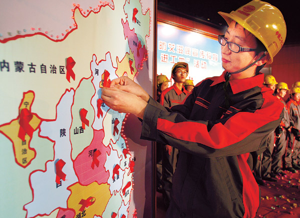 Migrant worker Qiu Zhenzhong marks the position of his hometown on a map of China with a red ribbon at an HIV/AIDS awareness-raising event at the construction site of the Shijingshan Hospital in Beijing on Tuesday.