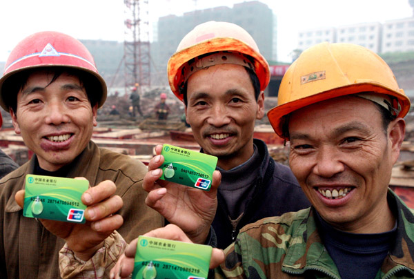 Migrant workers at a construction site in Huaying city of Sichuan province display their wage cards on Dec 14.