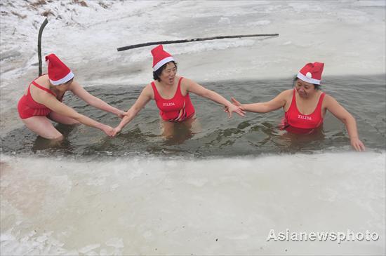 People dressed like Santa play in the chilly water of Hunhe River in Shenyang, Northeast China's Liaoning province, Dec 20, 2010. [Photo/Asianewsphoto]