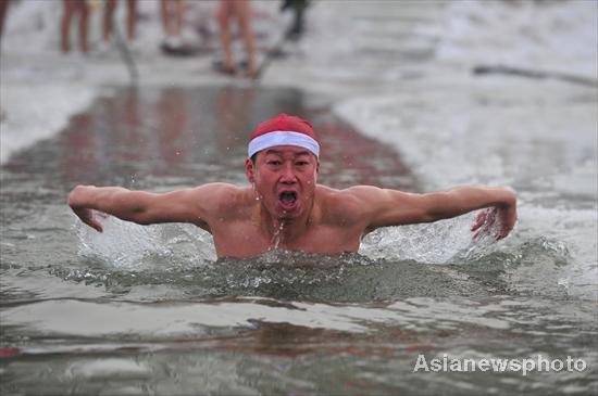 A man wearing a Santa Claus hat swims in the chilly water of Hunhe River in Shenyang, Northeast China's Liaoning province, Dec 20, 2010. [Photo/Asianewsphoto]