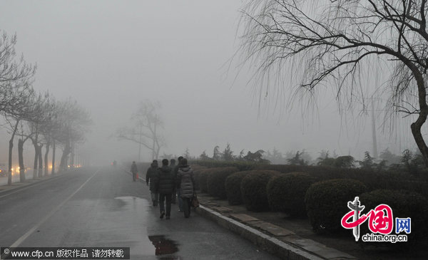 People walk in heavy fog in Dalian, Liaoning province, Dec. 22, 2010. [CFP]