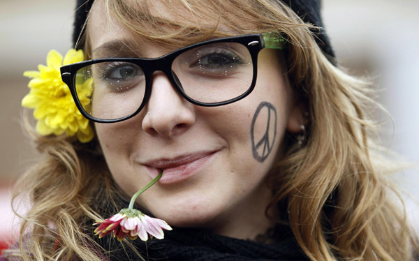 A student biting on a flower smiles during a demonstration in Rome, Dec 22, 2010. [China Daily/Agencies]