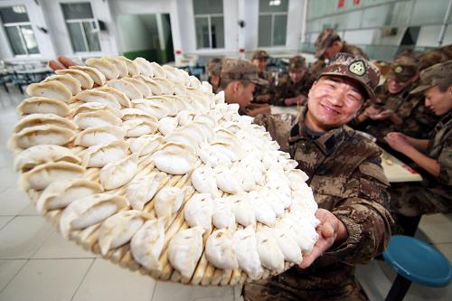 A soldier at Jinan military area command shows off a tray of homemade dumplings, Dec 21, 2010. [Xinhua]