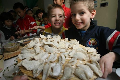 Two American boys show their homemade dumplings at a primary school in Jinan, East China’s Shandong province, Dec 21, 2010. [Xinhua]