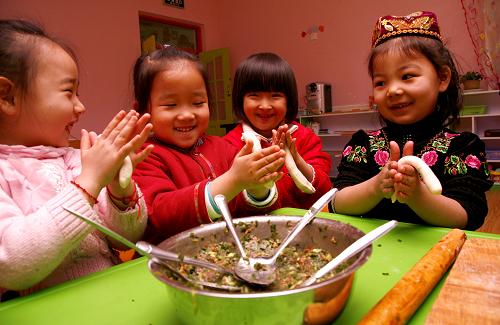 Children make dumplings at a kindergarten in Hami, Northwest China’s Xinjiang Uygur autonomous region, Dec 21, 2010. [Xinhua]