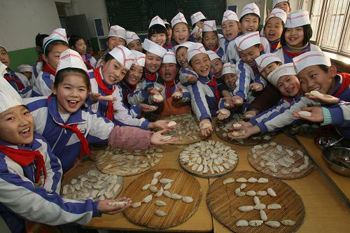 Children of migrant workers show their homemade dumplings at a primary school in Jinan, East China&apos;s Shandong province, Dec 21, 2010. [Xinhua]