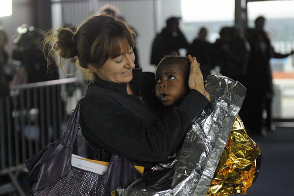 Delphine Riviere from Lyon holds her newly-adopted child Erika, one of the 113 orphans from Haiti who arrive in France, upon their arrival at the Roissy Airport, north of Paris, December 22, 2010. [China Daily/Agencies]