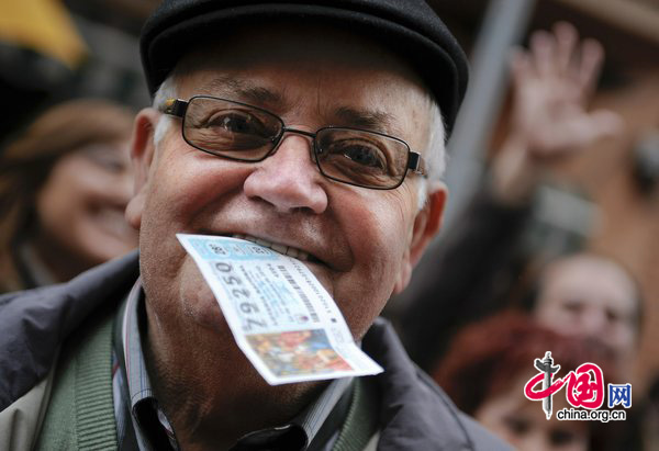 A winner of &apos;El Gordo&apos; bites his winning ticket at the bar which sold the largest amount of winning tickets for the spanish lottery on December 22, 2010 in Barcelona, Spain. [CFP]