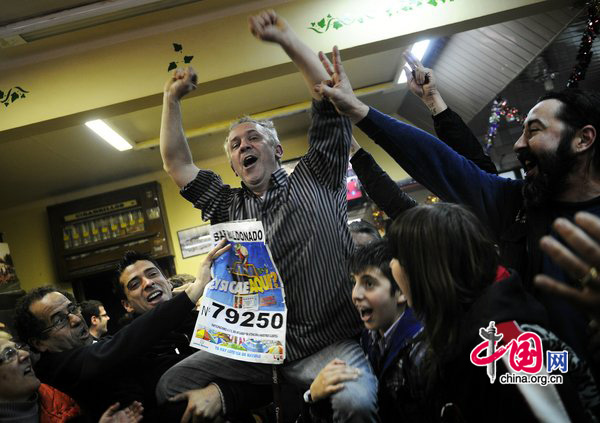 The owner of the bar (C) which sold the largest amount of winning tickets for the spanish lottery &apos;El Gordo&apos; celebrates with his clients on December 22, 2010 in Palleja, near Barcelona, Spain. [CFP]